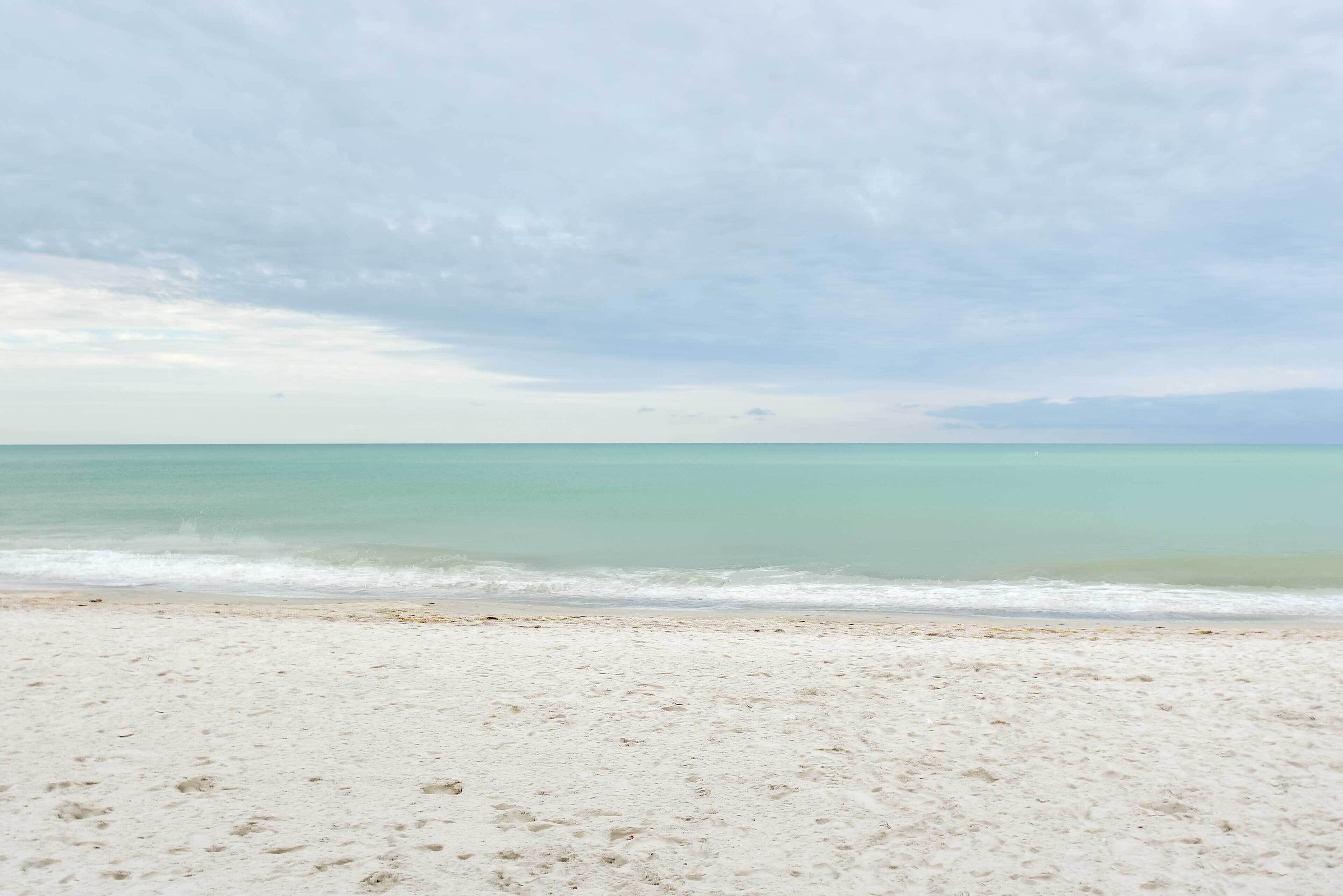 A beach with a sandy shore and calm ocean waves.