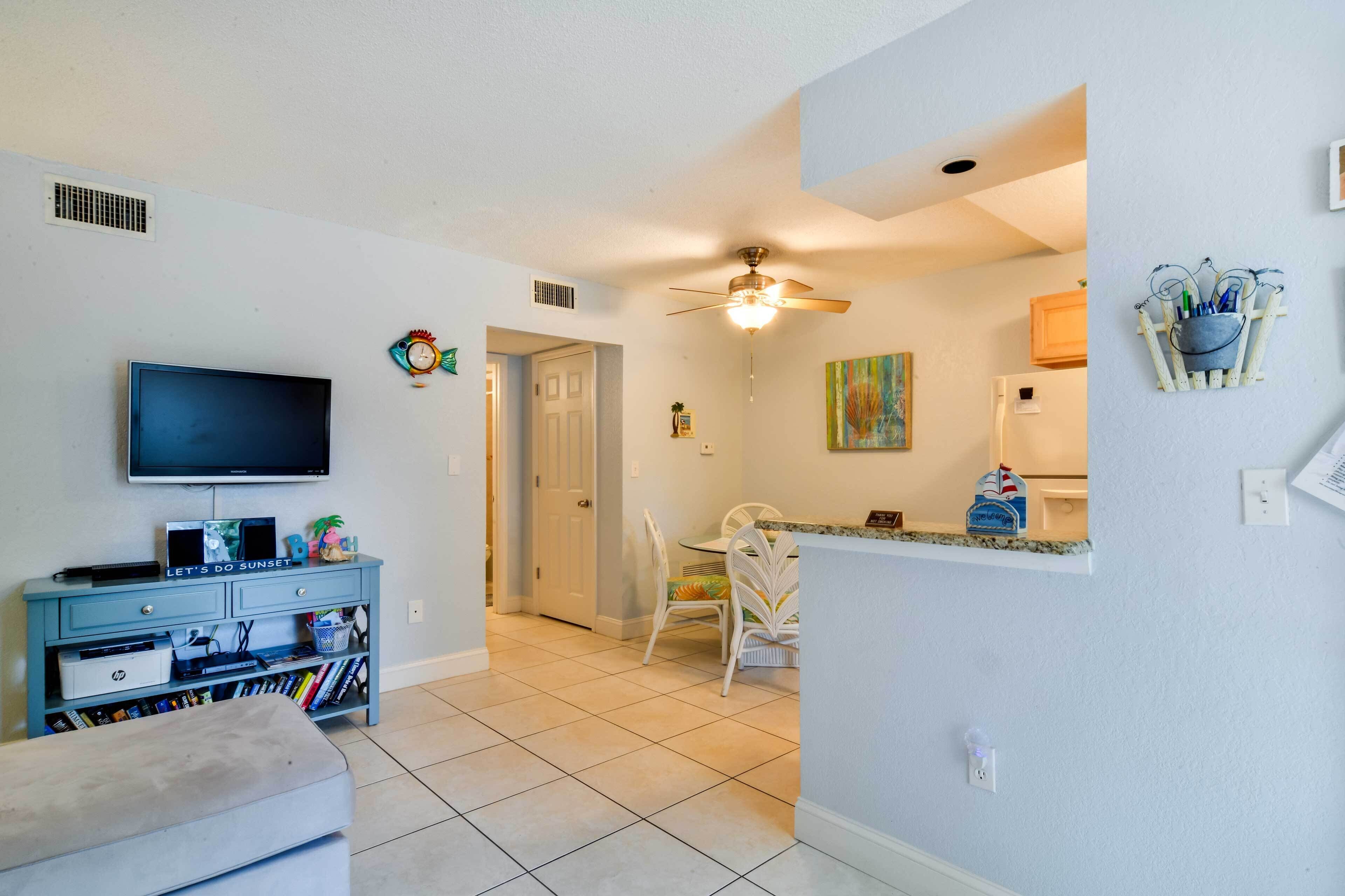 A living room with a flat-screen TV, a blue entertainment unit, and a white sofa.