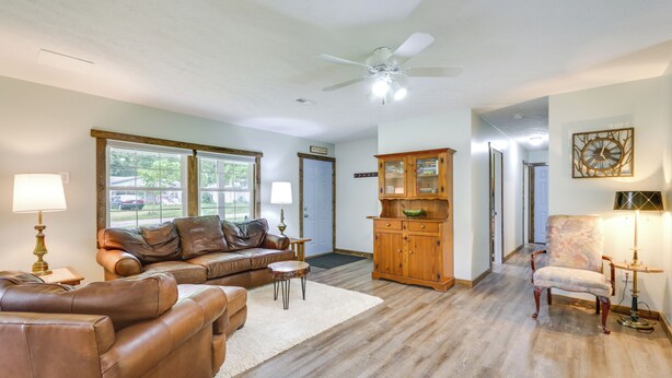 A spacious living room with leather sofas, a wooden cabinet, and a large window.