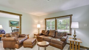 A living room with a brown leather sofa set, a round coffee table, and a lamp on a wooden side table.