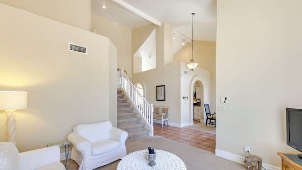 A spacious living room with a white sofa, a round coffee table, and a staircase leading to another level. - Pool & Spa! Goodyear Home, 1 Mi to Golfing (Goodyear)