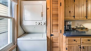 A laundry room with a front-loading washer and dryer, wooden cabinets, and a coffee maker on the counter. - Quaint 'gretna Getaway' Cottage w/ Screened Porch! (Lebanon)