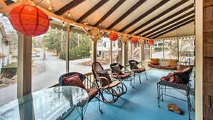 A covered outdoor seating area with wicker chairs and a glass table, overlooking a residential street. - Quaint 'gretna Getaway' Cottage w/ Screened Porch! (Lebanon)