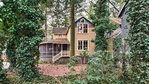 A two-story house with a porch and a fenced yard, surrounded by dense foliage. - Quaint 'gretna Getaway' Cottage w/ Screened Porch! (Lebanon)
