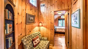 A wooden interior with a sofa, bookshelves, framed pictures, and a lamp. - Quaint 'gretna Getaway' Cottage w/ Screened Porch! (Lebanon)