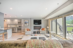 A modern kitchen with stainless steel appliances, a fireplace, and a dining area with a large window overlooking a garden.