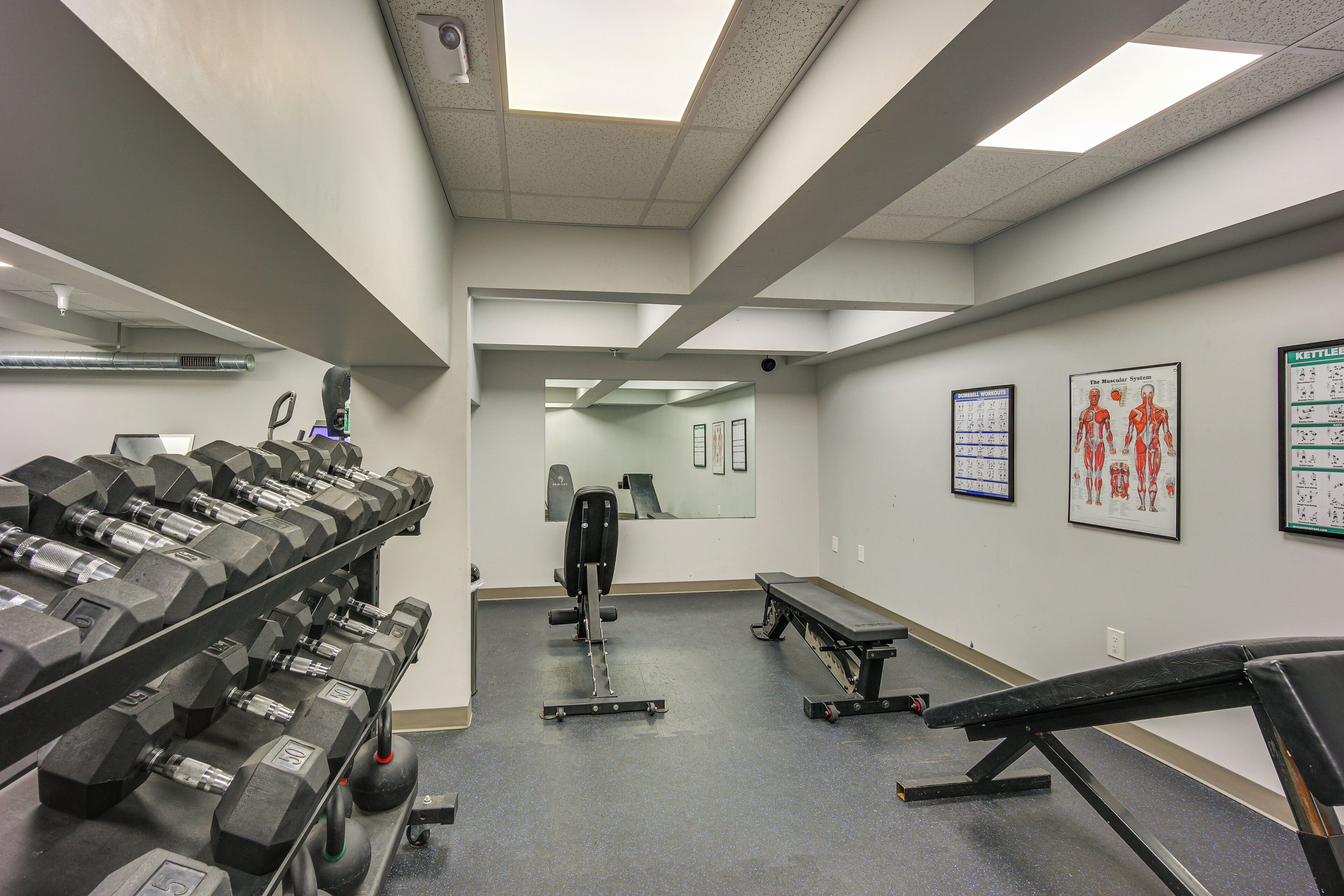Ein Fitnessstudio mit Gewährleistungsausrüstung, Trainingsgeräten und lehrreichen Postern an den Wänden.