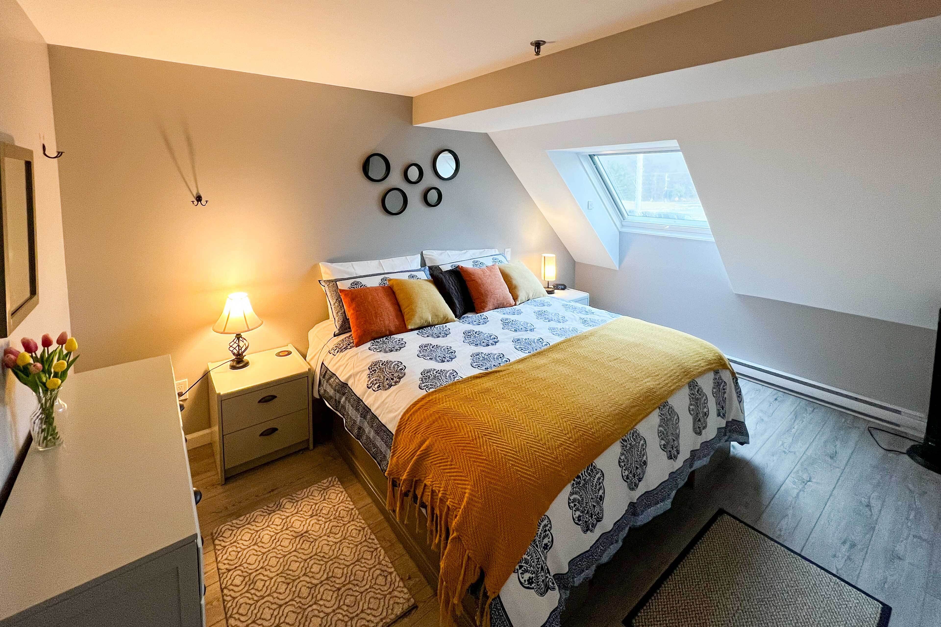 A bedroom with a bed, nightstand, lamp, and wall decor.