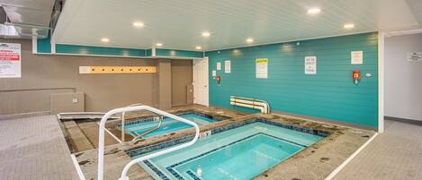 Una piscina cubierta con dos carriles, señalización de seguridad y un puesto de socorrista.