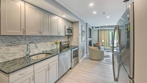 A modern kitchen with stainless steel appliances, a granite countertop, and a view into the dining area. - Walk to Lifts & Village! Killington Mountain Condo (Killington)