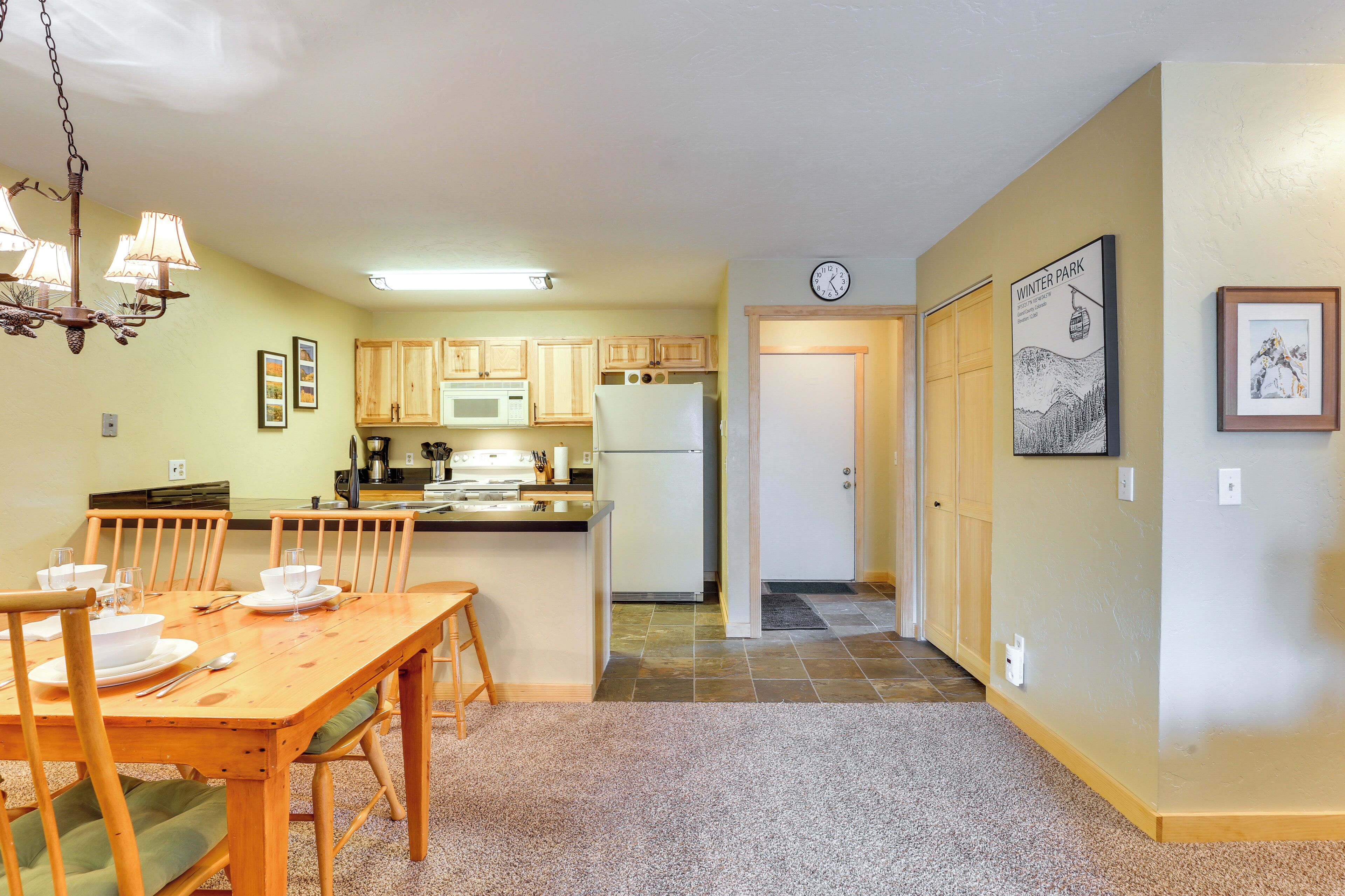 A compact kitchen with wooden cabinets, a central island, and a dining area with a wooden table and chairs.