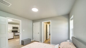 A bedroom with a bed, bedside table, and a view of the kitchen. - Convenient Tulsa Home - 2 Mi to Downtown! (Tulsa)