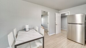 A modern kitchen with a stainless steel refrigerator, a marble-top dining table with chairs, and light wooden flooring. - Convenient Tulsa Home - 2 Mi to Downtown! (Tulsa)