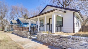 A single-story house with a front porch, a stone retaining wall, and a clear blue sky. - Convenient Tulsa Home - 2 Mi to Downtown! (Tulsa)