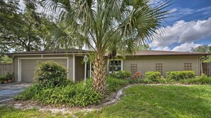 A single-story house with a garage, a well-maintained lawn, and a palm tree.