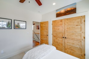 Un dormitorio con cama, armario de madera y dos cuadros en la pared.