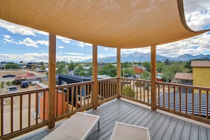 Una terrazza in legno con vista sulle montagne e su una città.