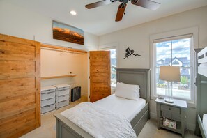 Quarto com cama, ventilador de teto, janela com vista e guarda-roupa de madeira.