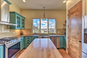 A kitchen with teal cabinets, a wooden countertop, stainless steel appliances, and a large window with a view. - Buena Vista Home w/ Mtn Views, Walk to Main St (Buena Vista)