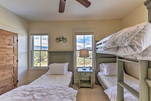 A bedroom with two single beds, a nightstand with a lamp, and a window with a mountain view. - Buena Vista Home w/ Mtn Views, Walk to Main St (Buena Vista)