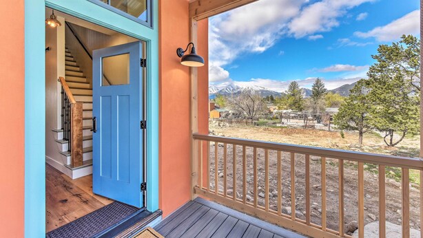 Una terraza de madera con una puerta azul que da a una escalera.