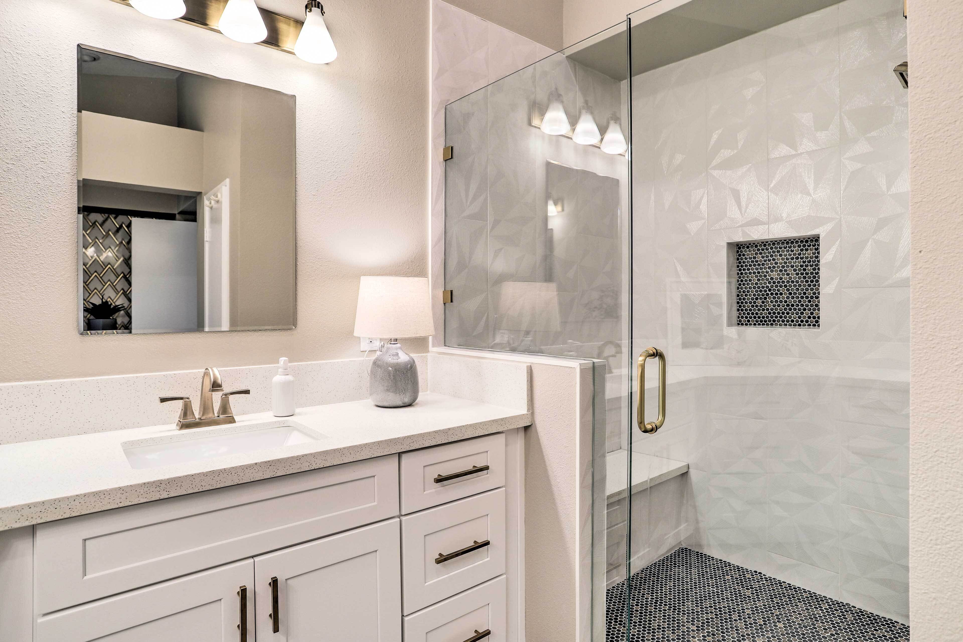 A modern bathroom with a glass-enclosed shower, a white vanity with a sink, and a mirror above the vanity.