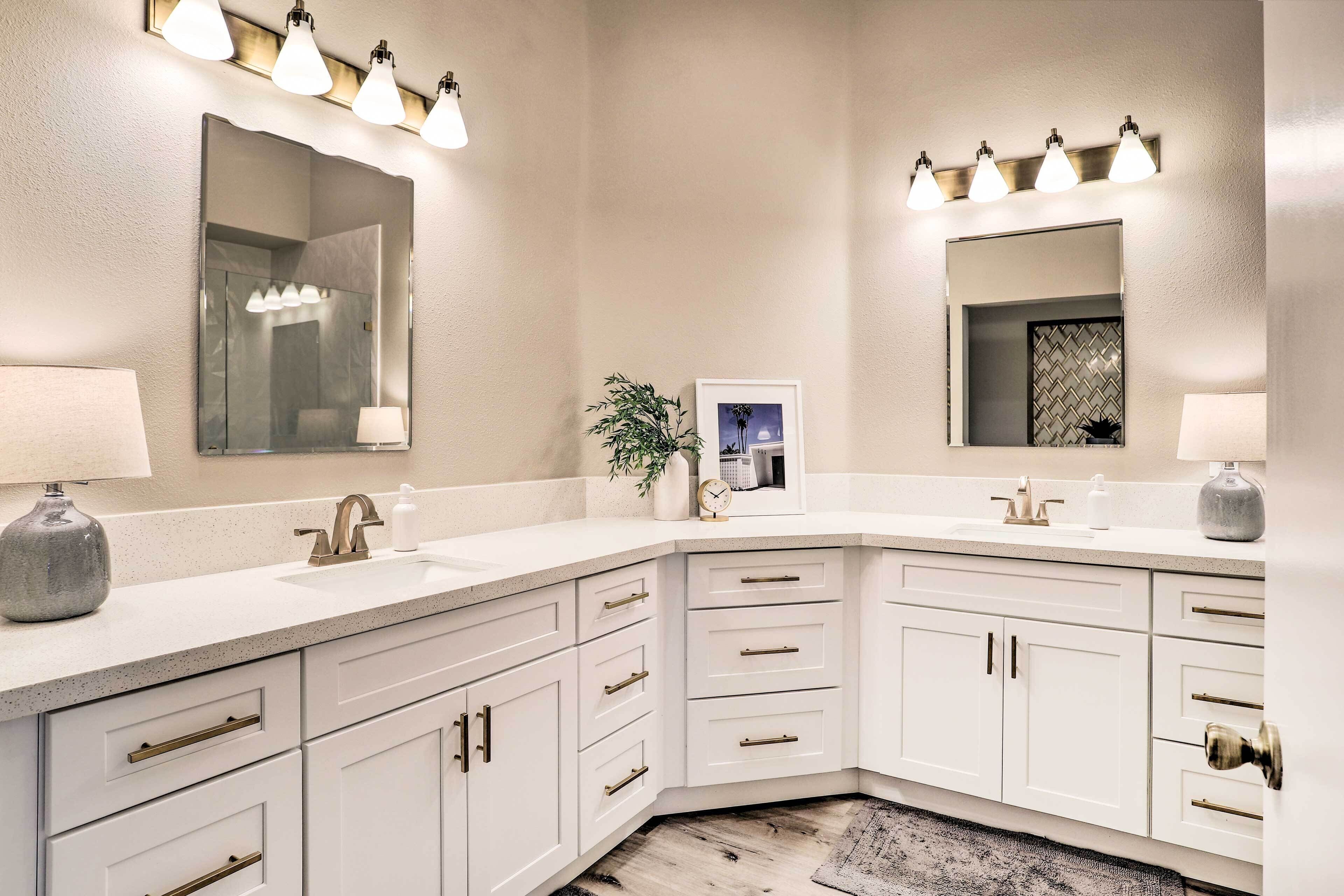 A modern bathroom with white cabinetry, a large mirror, and a corner sink.