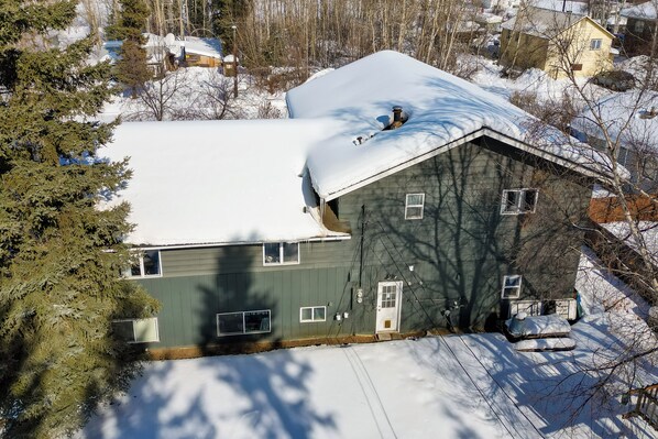 Une maison à deux étages, dont le toit est recouvert de neige, et qui possède un garage.