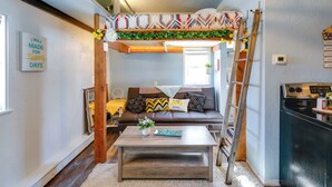 A cozy living space with a loft bed, a sofa, a coffee table, and a kitchen area. - 2 Mi to Dtwn & Pioneer Park: Fairbanks Studio! (Fairbanks)