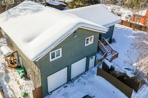 Una casa de dos pisos con techo nevado y un garaje.