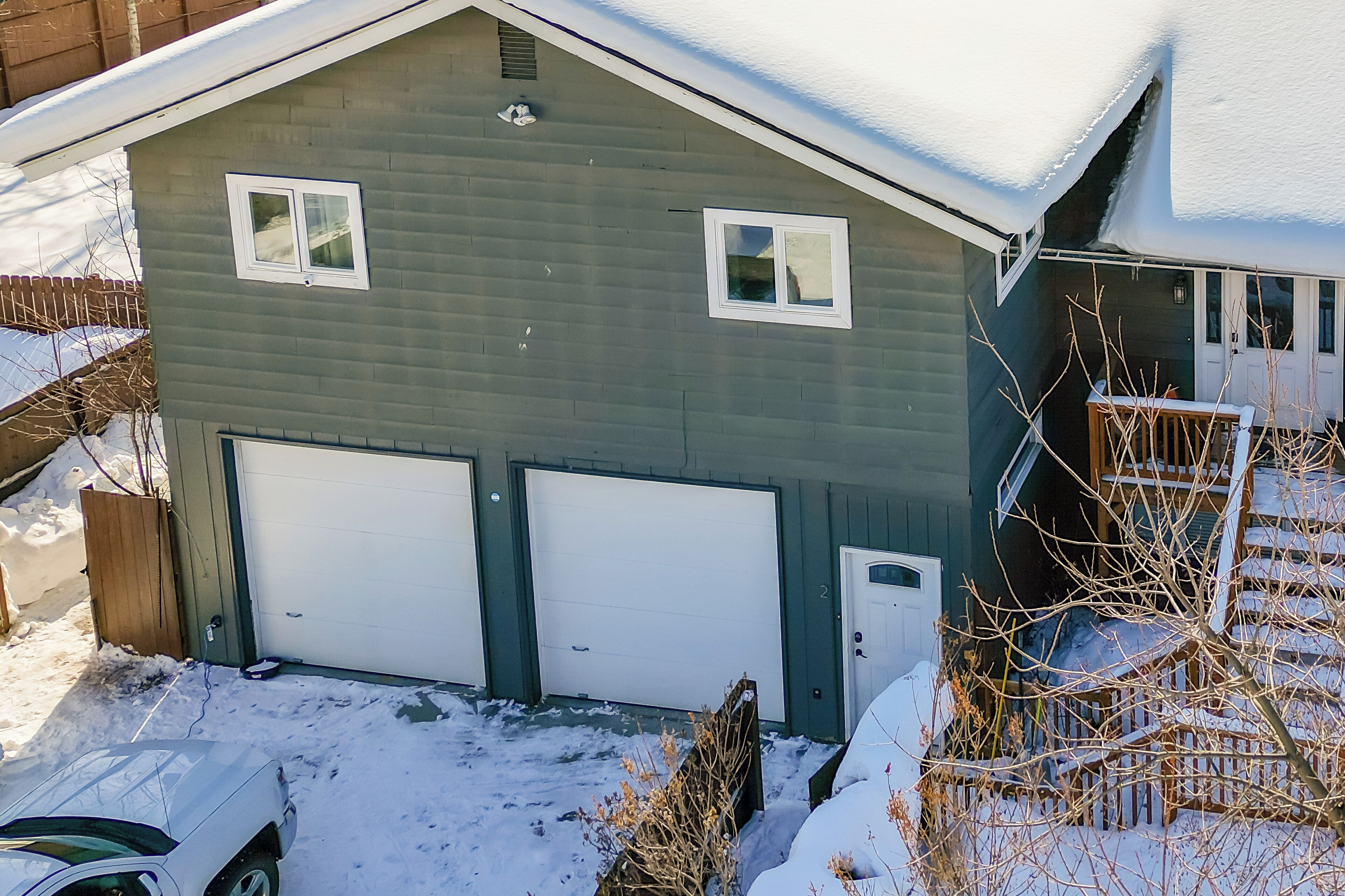 A two-story house with a garage, a covered porch, and a snow-covered roof.