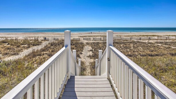 A wooden staircase leading to a beach with a clear blue sky.