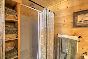 A wooden interior with a shower curtain, a towel rack with a towel, and a shelf with folded towels. - 'valley View Cabin' Near Branson & Table Rock Lake (Omaha)