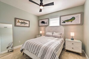 Ein Schlafzimmer mit Bett, Nachttischen, Deckenventilator und Wandbild.