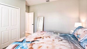 Una camera da letto con un letto, una ventola a soffitto, un comodino e una lampada a parete.
