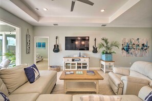 A living room with a beige sofa, a coffee table, a TV, and a bookshelf. - 5 Mi to Beach & Walk to Park: Modern Venice Home (Venice)