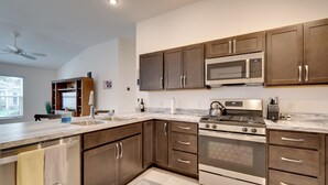 A modern kitchen with dark wooden cabinets, stainless steel appliances, and a marble countertop. - Sun-soaked Retreat in The Villages w/ Grill! (Coleman)
