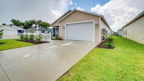 A single-story house with a garage, surrounded by well-maintained lawns and a clear sky. - Sun-soaked Retreat in The Villages w/ Grill! (Coleman)
