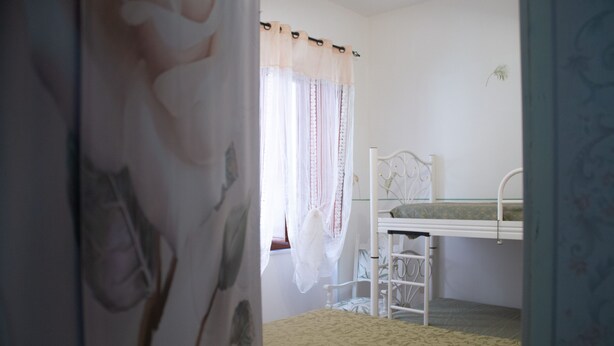 A bedroom with a bunk bed, a chair, and a window with curtains. - Casa Vacanze da Vicenta (Camerota)