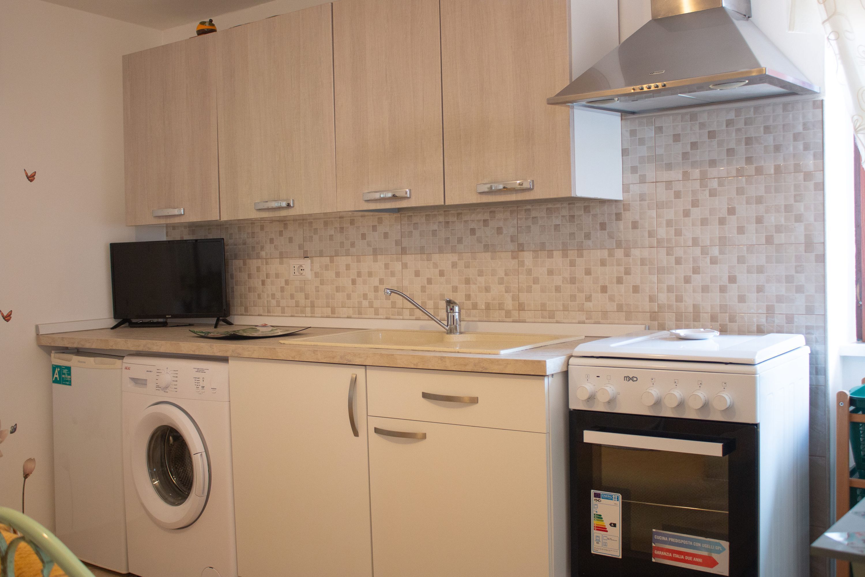 Une cuisine compacte équipée d’un lave-linge, d’une cuisinière et d’un four à micro-ondes.