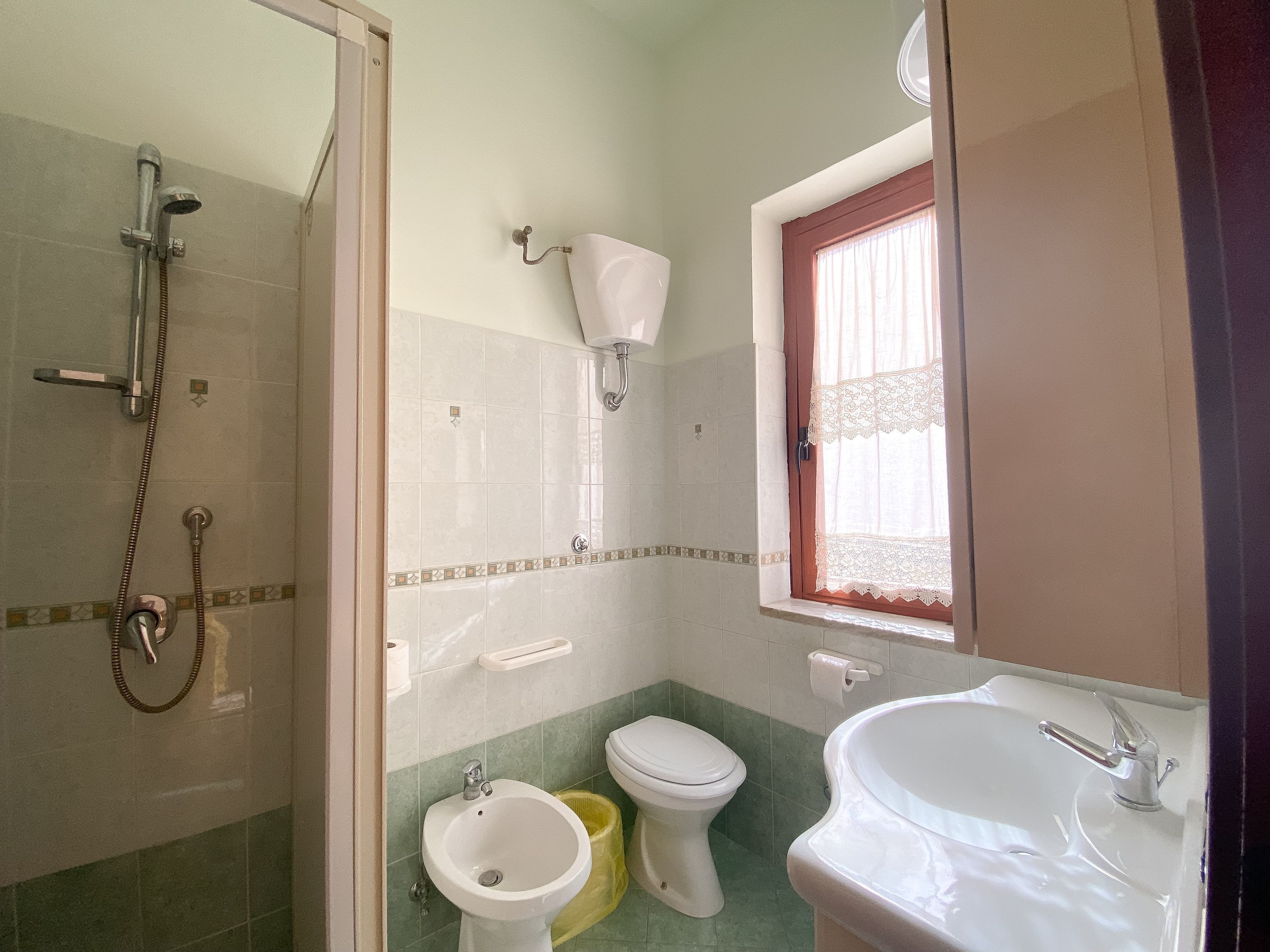 Et badeværelse med bruser, toilet, bidet og vask.
