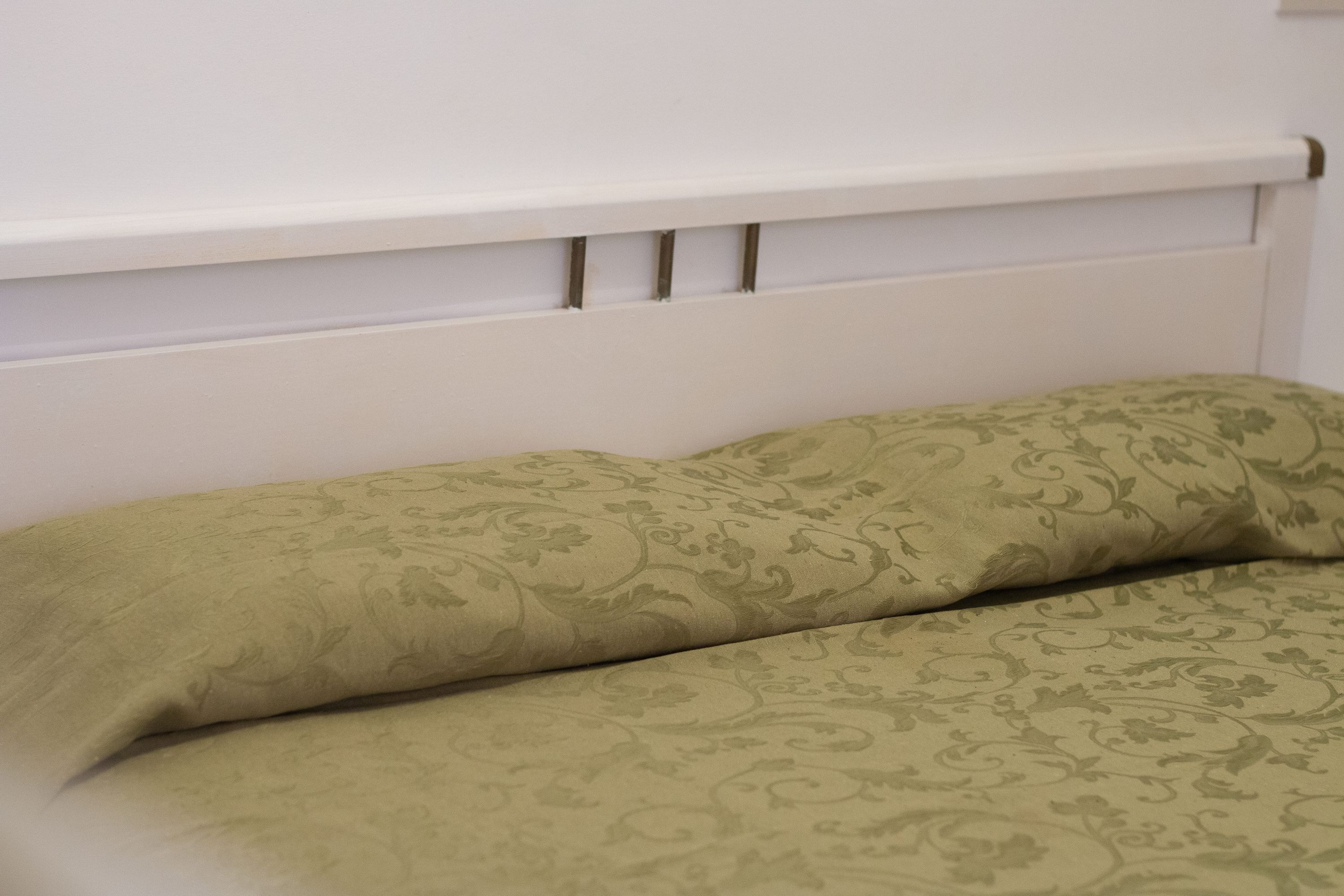 A bed with a patterned bedspread and a white headboard.