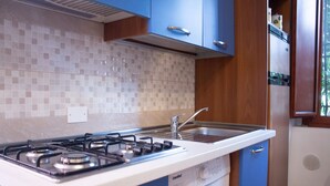 A compact kitchen with a gas stove, a sink, and a washing machine. - Casa Vacanze da Vicenta (Camerota)