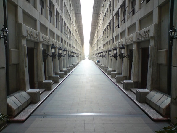 Un largo pasillo recto con luminarias uniformes y puertas numeradas a ambos lados.