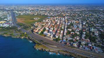 An aerial view of a coastal city with a dense residential area, a major highway, and a coastline.