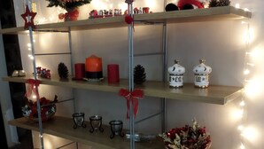 Une étagère métallique à plusieurs niveaux, agrémentée de divers objets décoratifs, notamment un petit sapin de Noël, des bougies et des figurines.