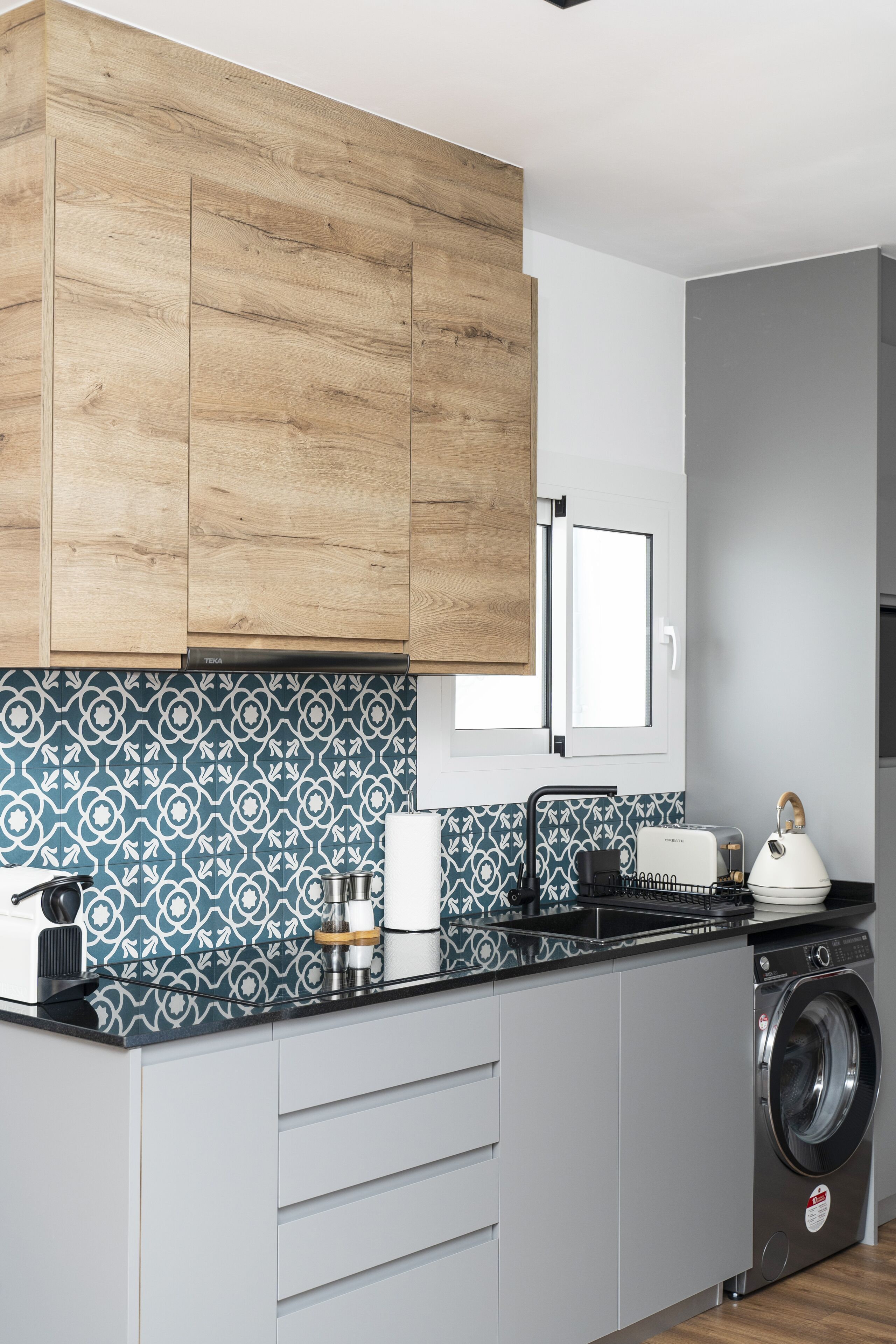 A modern kitchen with wooden cabinets, a patterned backsplash, and a built-in washing machine.