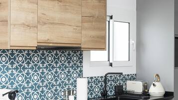 A modern kitchen with wooden cabinets, a patterned backsplash, and a built-in washing machine.