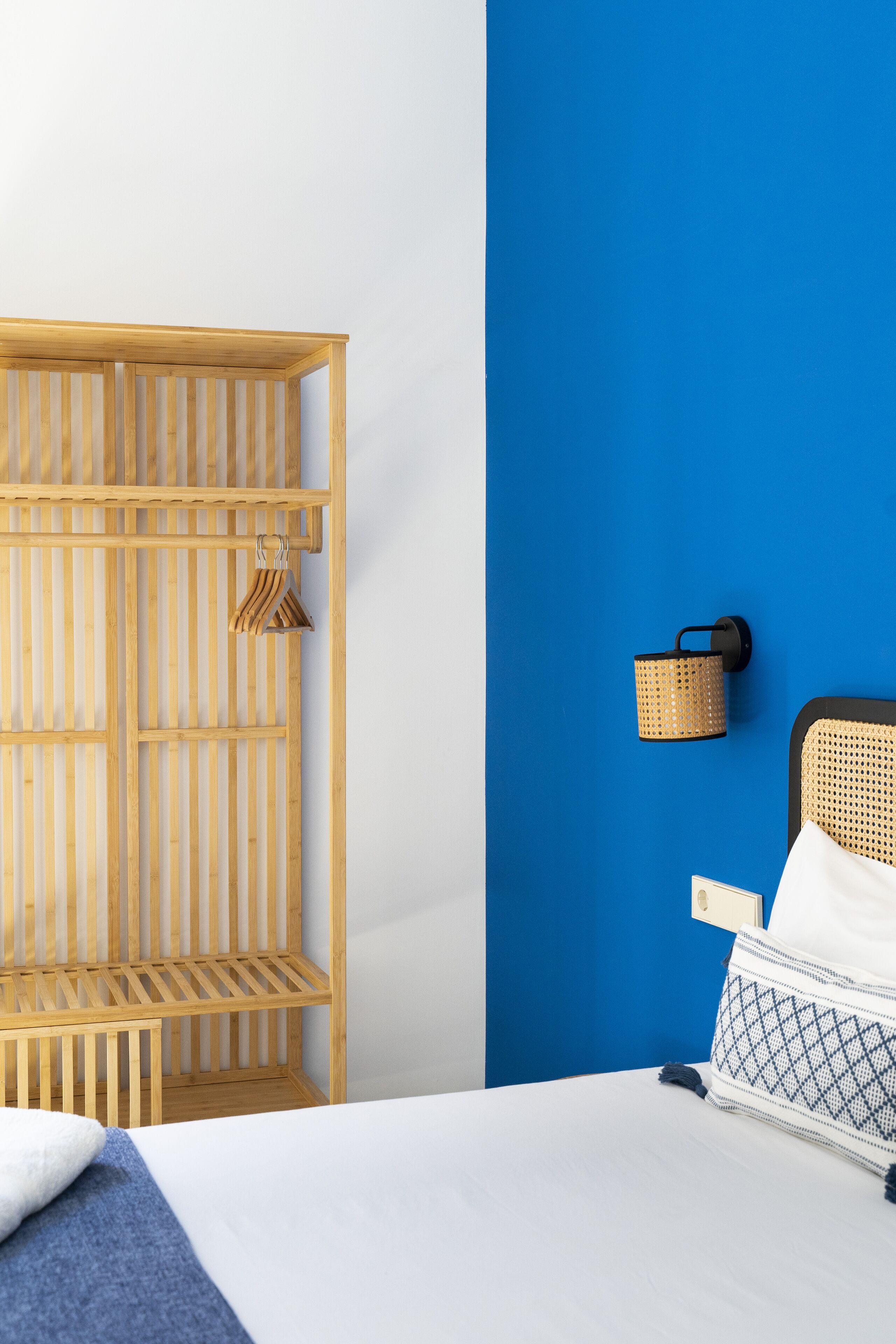 Una habitación con cama, armario de madera y pared azul de acento.