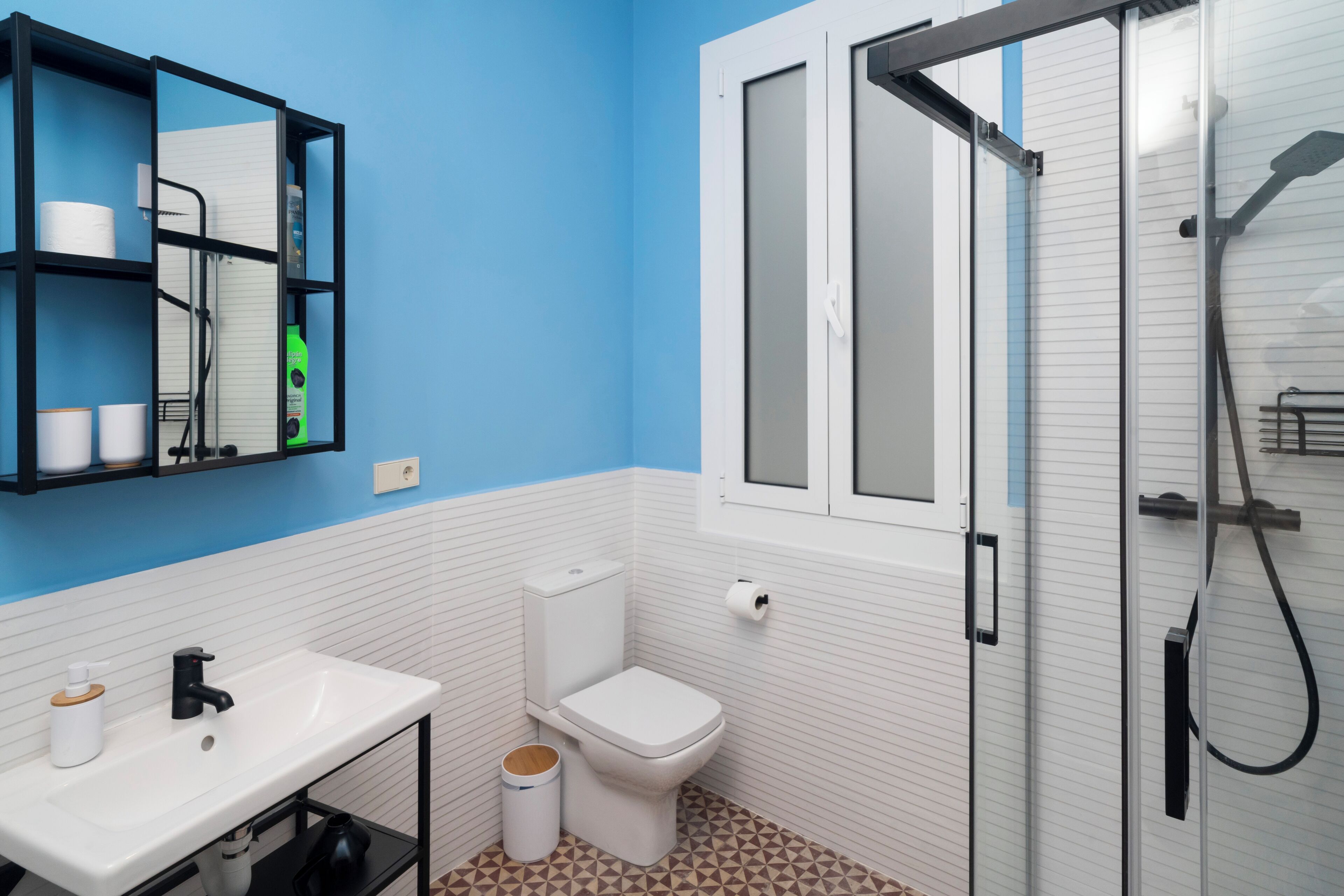 Un baño con lavamanos blanco, inodoro, espejo y zona de ducha.